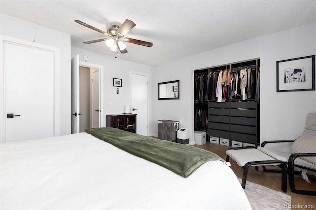 bedroom with ceiling fan, wood-type flooring, a closet, and a textured ceiling