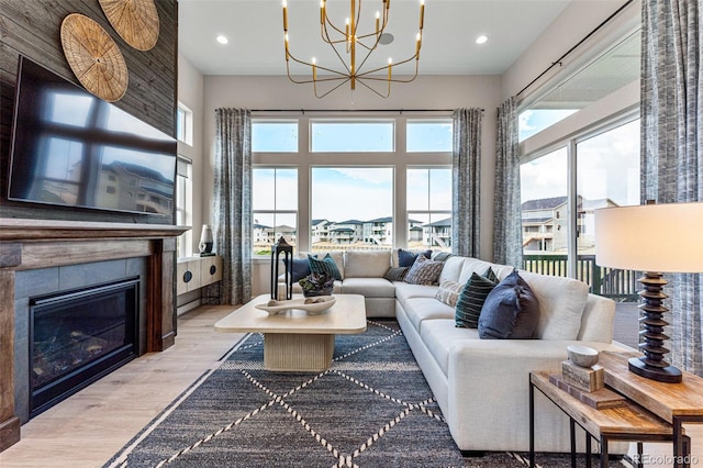 living room with a fireplace, light wood-type flooring, a chandelier, and a wealth of natural light