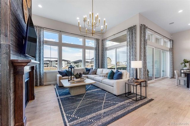 living room featuring a towering ceiling, an inviting chandelier, and light wood-type flooring