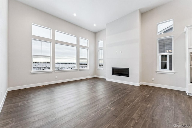 unfurnished living room featuring dark hardwood / wood-style flooring and a towering ceiling