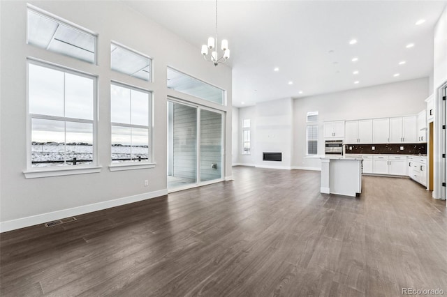 unfurnished living room featuring a chandelier, wood-type flooring, and a towering ceiling