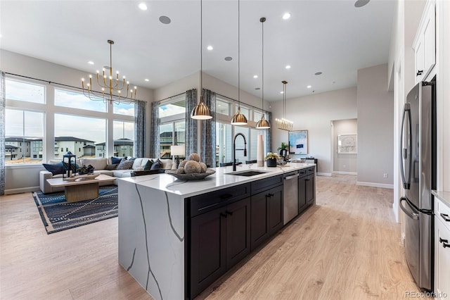 kitchen featuring pendant lighting, a center island with sink, sink, light hardwood / wood-style flooring, and appliances with stainless steel finishes