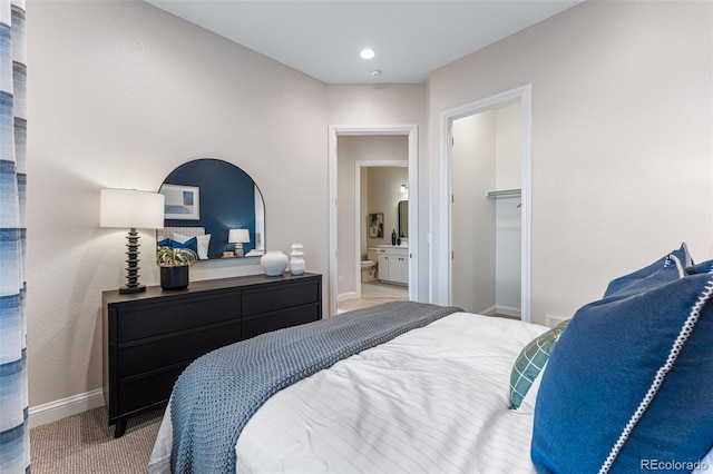 bedroom featuring carpet flooring, a walk in closet, ensuite bathroom, and a closet