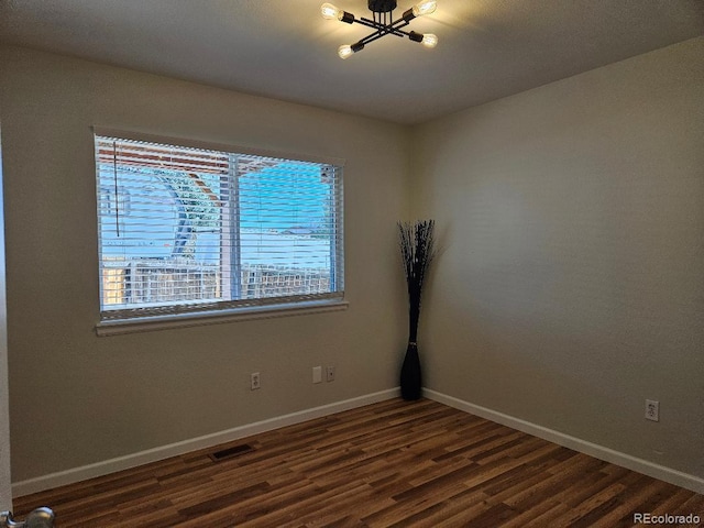 808 Idalia St, Aurora, CO 80011 - empty room with dark wood finished floors, baseboards, and a chandelier