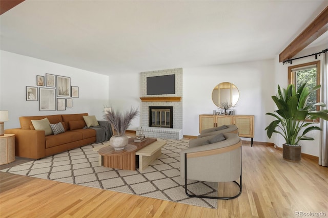 living room featuring light hardwood / wood-style flooring, beamed ceiling, and a fireplace