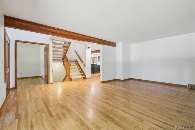 empty room featuring light hardwood / wood-style floors and beamed ceiling