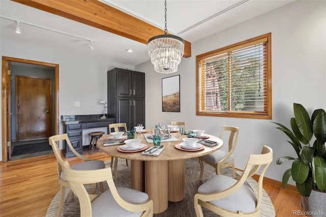 dining area featuring a notable chandelier, light wood-type flooring, beam ceiling, and rail lighting