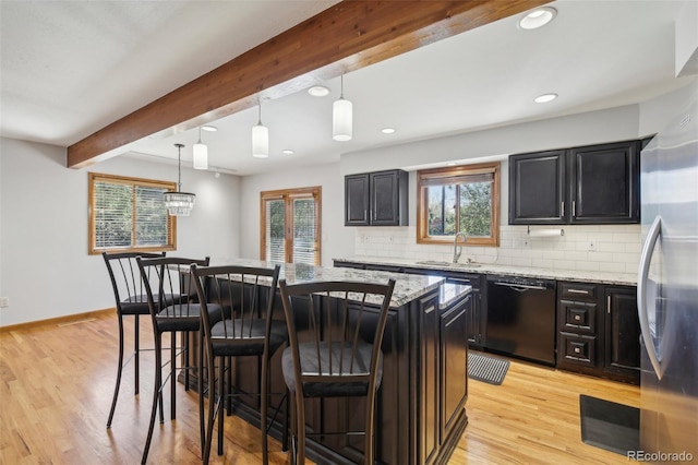 kitchen featuring a breakfast bar, pendant lighting, black dishwasher, light stone counters, and sink