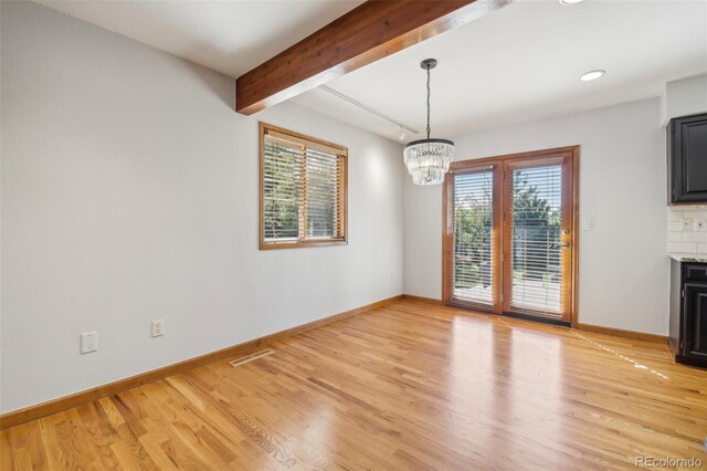 unfurnished dining area featuring beamed ceiling, a chandelier, and light hardwood / wood-style floors