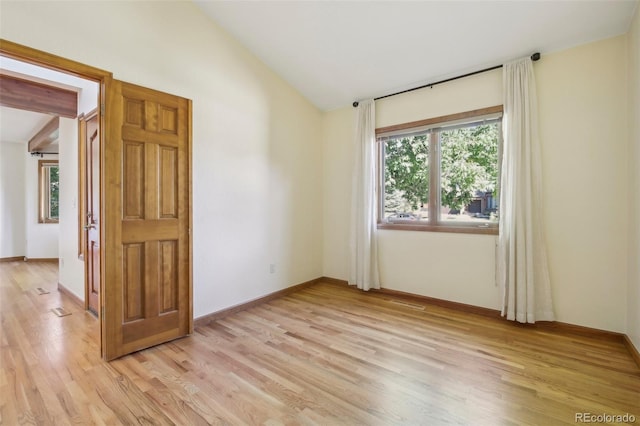 unfurnished room featuring light wood-type flooring and vaulted ceiling