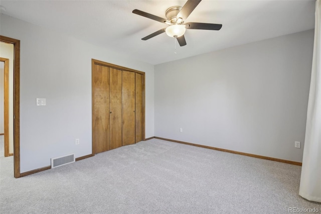 unfurnished bedroom featuring ceiling fan, light colored carpet, and a closet