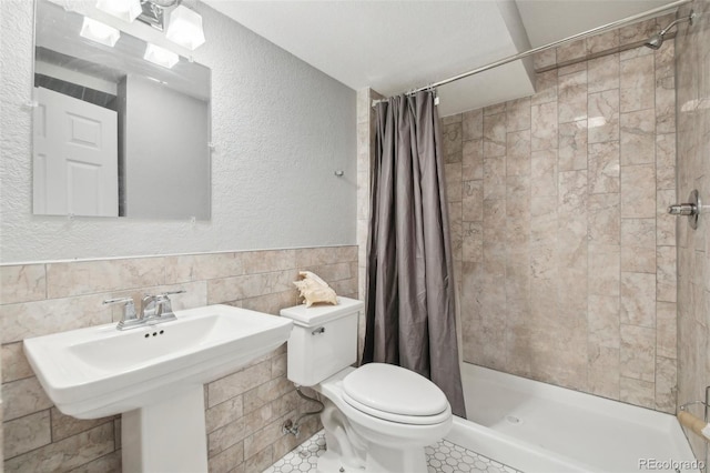 bathroom with tile walls, toilet, and a shower with shower curtain