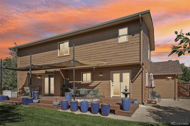 back house at dusk with a patio and a yard