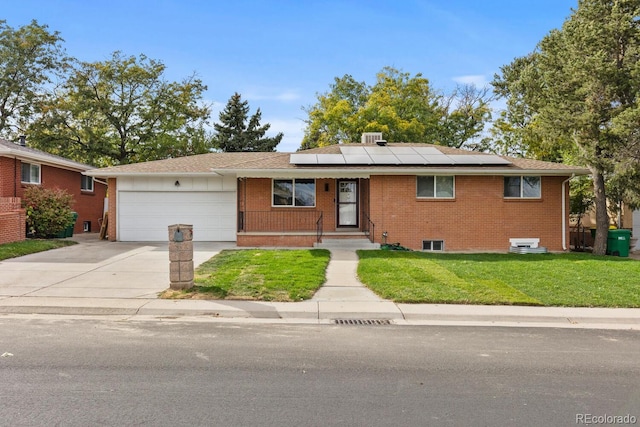 ranch-style home with solar panels, a front yard, and a garage