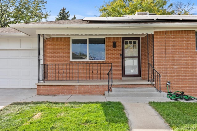 doorway to property featuring a garage, roof mounted solar panels, and brick siding