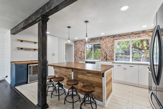 kitchen with white cabinetry, wooden counters, and brick wall