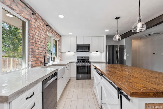 kitchen with brick wall, a kitchen island, stainless steel appliances, and a healthy amount of sunlight