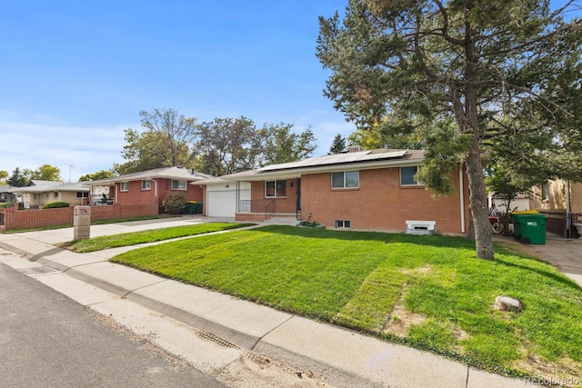 ranch-style house with solar panels, a front yard, and a garage