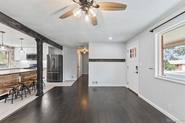 unfurnished living room featuring ceiling fan, a healthy amount of sunlight, beamed ceiling, and hardwood / wood-style floors