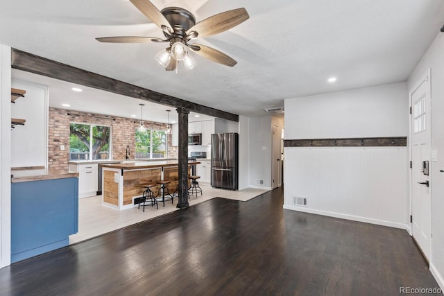 kitchen featuring white cabinetry, stainless steel appliances, wood-type flooring, and decorative light fixtures