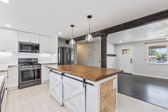 kitchen featuring beam ceiling, a center island, appliances with stainless steel finishes, and white cabinetry