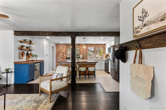 kitchen with beverage cooler, appliances with stainless steel finishes, beamed ceiling, a textured ceiling, and blue cabinetry