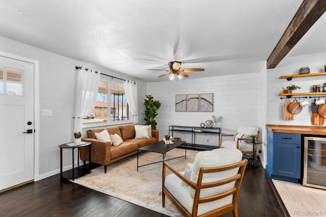 living room featuring a textured ceiling, wine cooler, a ceiling fan, light wood-style floors, and a dry bar