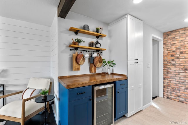 bar with a dry bar, light wood-style floors, wooden walls, brick wall, and beverage cooler