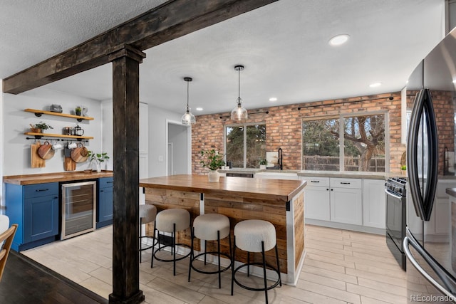 kitchen with wine cooler, a sink, wooden counters, and black appliances