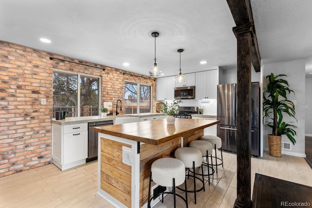 kitchen with light wood finished floors, a breakfast bar, stainless steel appliances, wooden counters, and a sink