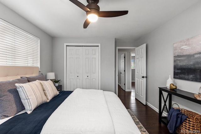 bedroom featuring a ceiling fan, baseboards, multiple windows, a closet, and dark wood finished floors