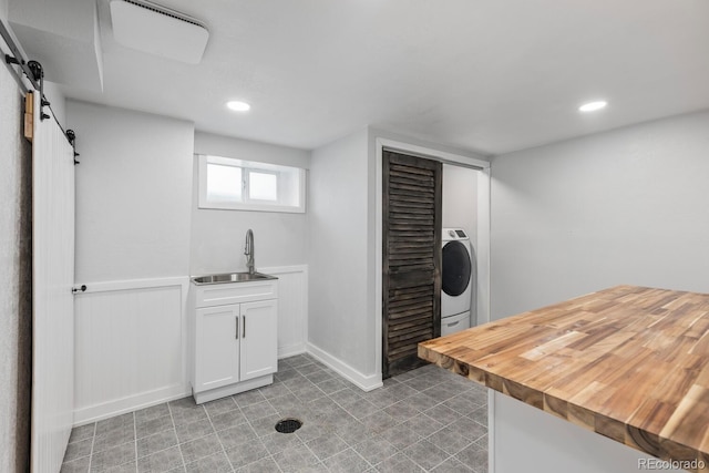 clothes washing area with a barn door, recessed lighting, laundry area, a sink, and washer / dryer