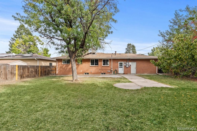 back of house with a patio, brick siding, a lawn, and fence