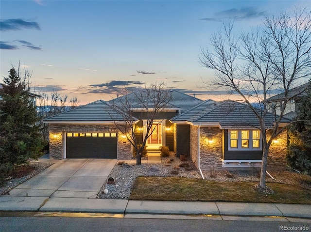 view of front of home featuring concrete driveway, stone siding, an attached garage, and a tiled roof