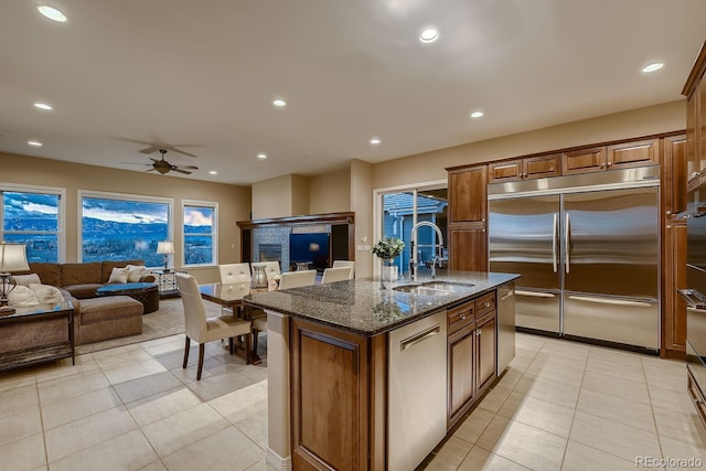 kitchen with open floor plan, stainless steel appliances, dark stone counters, and a sink