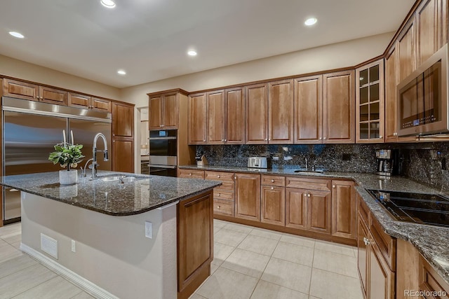 kitchen with stainless steel appliances, brown cabinetry, a sink, and backsplash