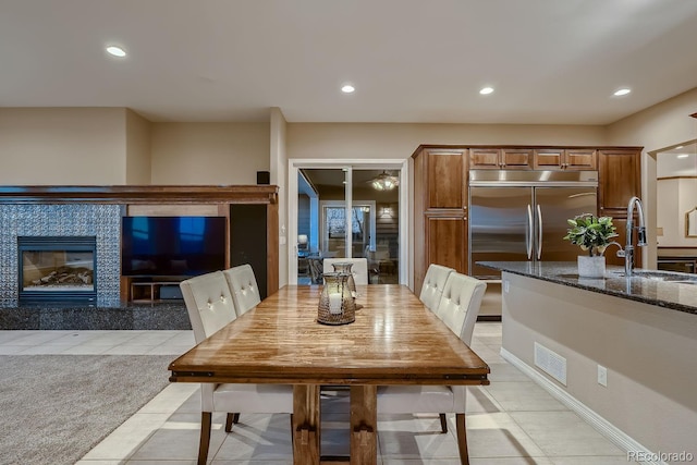 dining room with light tile patterned floors, visible vents, a tiled fireplace, light colored carpet, and recessed lighting