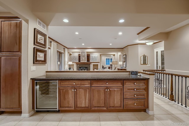 kitchen with visible vents, brown cabinetry, wine cooler, a fireplace, and recessed lighting