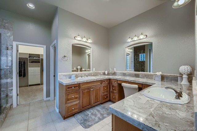 full bath with double vanity, a stall shower, a spacious closet, and a sink