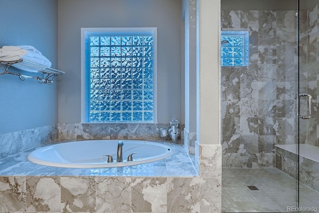 bathroom featuring a healthy amount of sunlight, a garden tub, and a shower stall