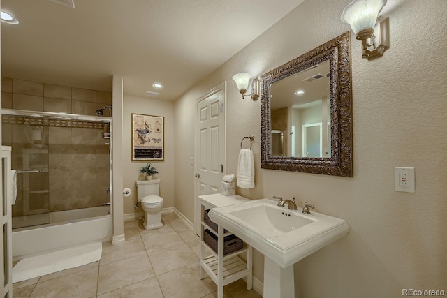 bathroom featuring toilet, shower / bath combination with glass door, a sink, baseboards, and tile patterned floors