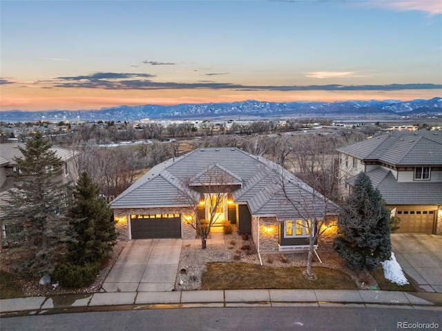 view of front of property featuring driveway, a tile roof, a garage, and a mountain view