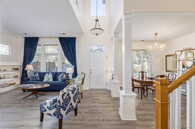 entryway with hardwood / wood-style flooring, ornate columns, and an inviting chandelier