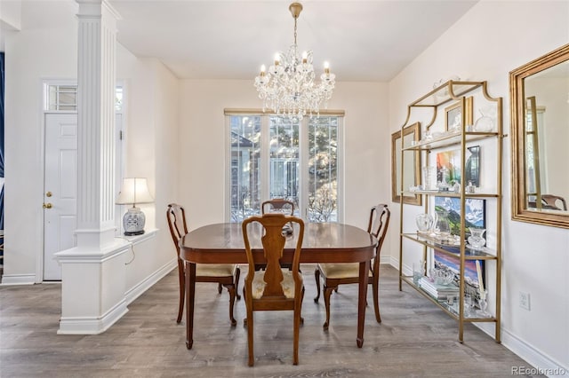 dining space with a notable chandelier, hardwood / wood-style flooring, and ornate columns