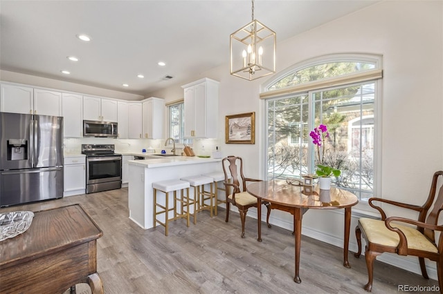 kitchen featuring pendant lighting, kitchen peninsula, white cabinets, and stainless steel appliances