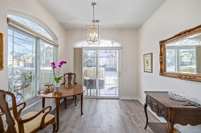 doorway to outside with light hardwood / wood-style floors and an inviting chandelier