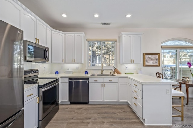 kitchen with sink, white cabinets, kitchen peninsula, and appliances with stainless steel finishes