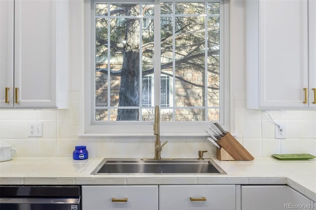 kitchen with sink, dishwashing machine, white cabinets, and decorative backsplash