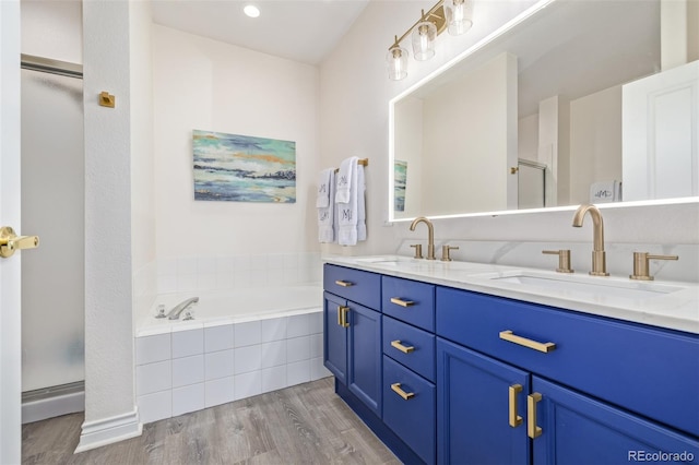 bathroom featuring wood-type flooring, plus walk in shower, and vanity