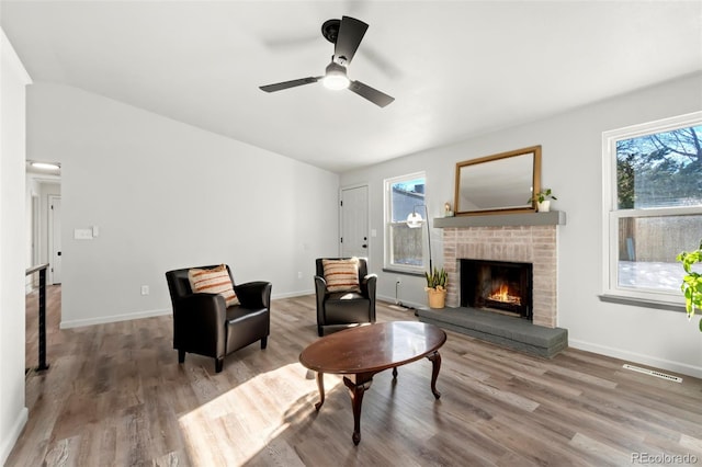 living room with ceiling fan, hardwood / wood-style floors, and a fireplace